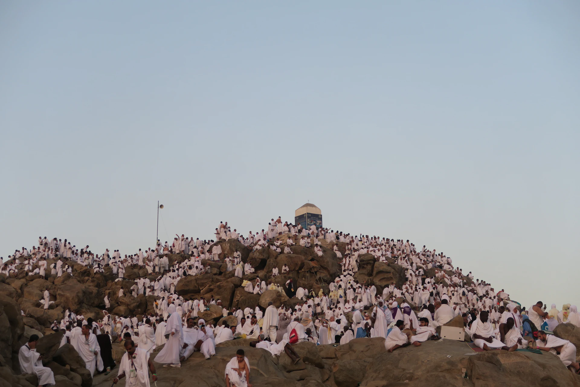 Pilger in weißem Ihram bedecken in der Abenddämmerung den Felshügel Jabal ar-Rahma in der Ebene von Arafat.